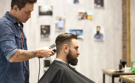 Barbering student using hair clippers on client