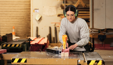 Carpentry student using saw to cut wood